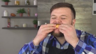 Sakallı şişman adam hevesle bir portakal yiyor ve tadı sahiptir, kamera, ağır çekim, lezzet görünüyor