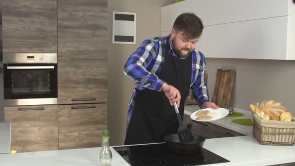 L'uomo barbuto cucina in cucina, pomiciando hamburger in una padella, facendo cotolette, slow mo, professionale — Video Stock