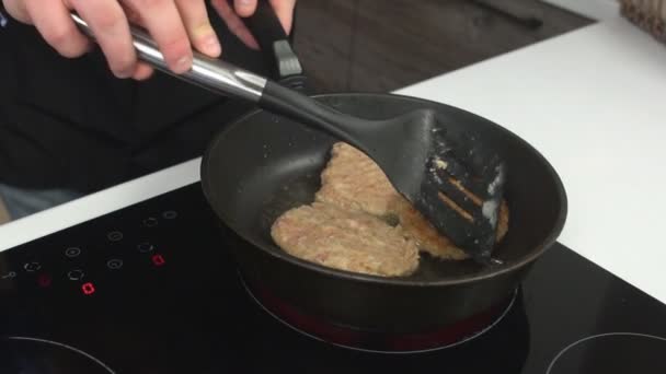 Мужчина-повар жарит котлеты в сковороде в оливковом масле и переворачивает их, замедленное движение — стоковое видео