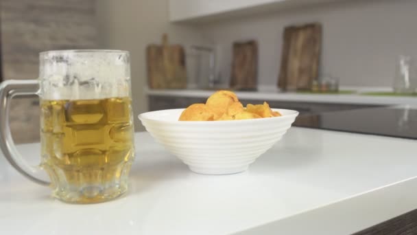 En la cocina hay un vaso de cerveza y un plato de papas fritas, obesidad y cerveza, espacio para copiar — Vídeo de stock