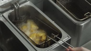 yeniden Restoran fritöz yavaş hareket, kafeler mutfakta yemek patates kızartması sebze yağ parçaları ayçiçeği yağında kızarmış patates yakından yağlı ve yüksek kalori lokanta