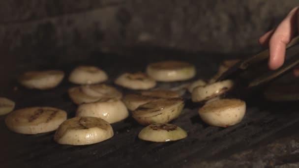 Cocinar papas fritas cebollas cortadas en parrilla barbacoa o en el interior del horno sobre carbones en la cafetería en slow mo, cerca de cebolla en rodajas se asan en el horno de mampostería sobre carbón a cámara lenta en los restaurantes cocina — Vídeos de Stock