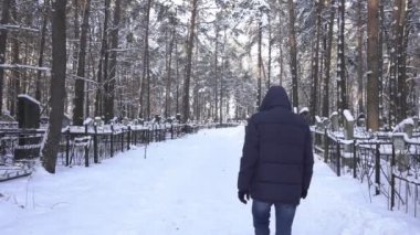 Üzgün adam kış soğuk mezarlığın içinden, açık yürür