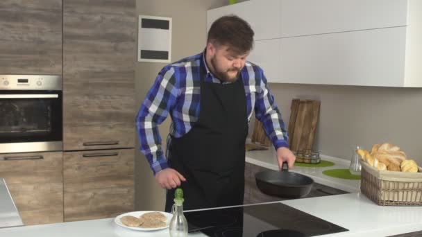 En man med ett skägg i det moderna köket förbereder sig för att steka köttbullar, olivolja, långsamma mo — Stockvideo