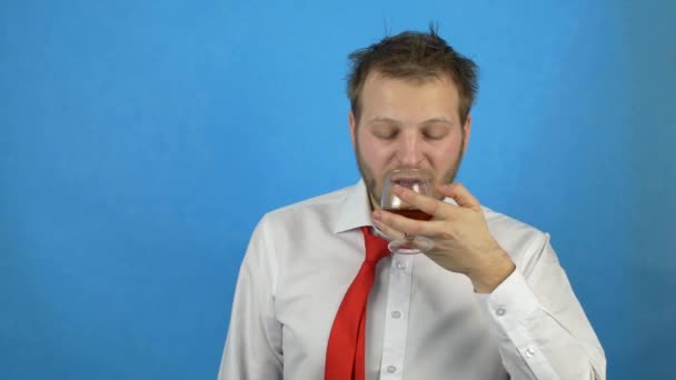 Um jovem com uma barba em uma camisa branca e gravata segura um copo com álcool e quer beber, mas é interrompido, codificação de álcool, falha contra o álcool — Vídeo de Stock