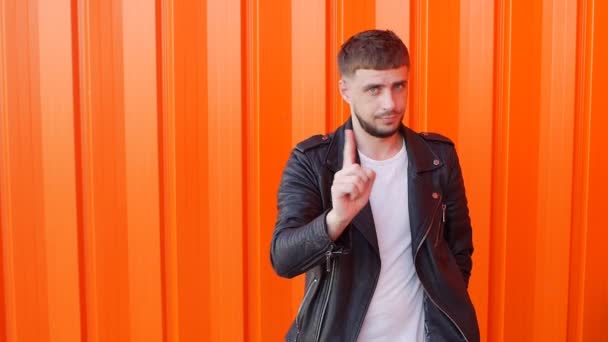 Joven caucásico con barba agitando el dedo y mostrando prohibición, negación, fondo naranja, slow-mo, prohibición — Vídeos de Stock