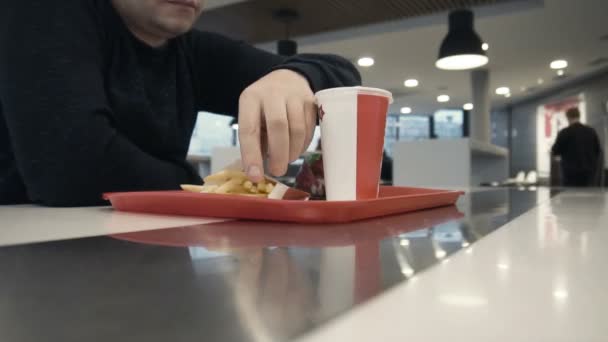 Hongerige man eten frietjes in fast-food restaurant — Stockvideo