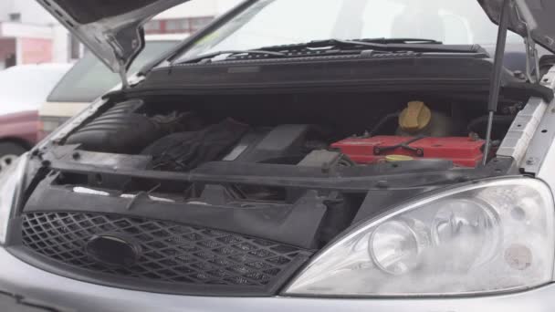 Um homem conecta fios de alta tensão de um carro doador para carregar um motor de carro com uma bateria descarregada, início do salto — Vídeo de Stock