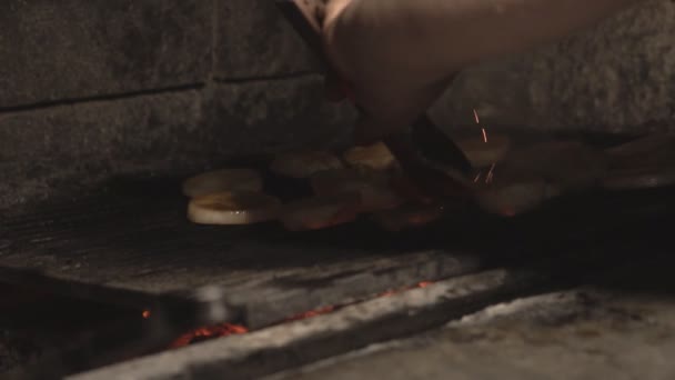 Μάγειρας στο εστιατόριο πατάτες κομμένα κρεμμύδια σε μπάρμπεκιου σχάρα σε φούρνο τούβλο πάνω σε κάρβουνα σε slowmo, εσωτερικη κρεμμύδι κομμένο σε φέτες ψήνονται στη σχάρα μέσα στο φούρνο τοιχοποιίας σε αργή κίνηση στην κουζίνα καφέ — Αρχείο Βίντεο