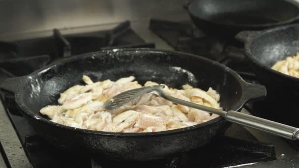 Onderdelen van filet kippenvlees gebakken of gekookt in een koekenpan of koekepan in de keuken van het restaurant op het gasfornuis in slow motion — Stockvideo
