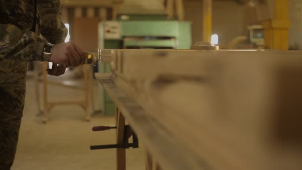 Trabajador aplica pegamento a una estructura de madera en el taller de muebles — Vídeo de stock