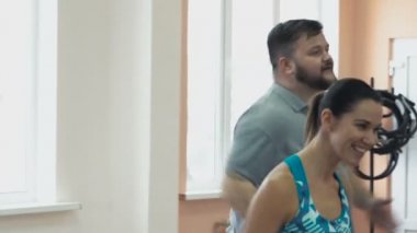 Kişisel ince Koç ile birlikte kalın obez adam fiziksel pislik içinde jimnastik salonu var. Kusursuz bir beden ile kilolu erkek ve kadın eğitmen tarafından egzersiz kalori yakmak. Kişisel eğitim için atletik kız dan