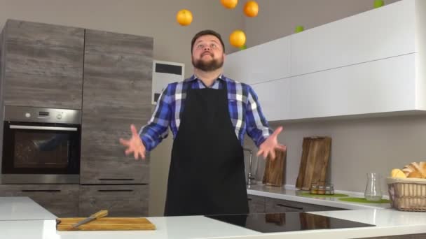 Blanc cuisinier masculin dans un tablier jongle oranges dans une cuisine moderne, au ralenti — Video