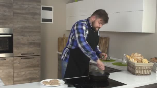 Un cuoco maschio caucasico con la barba prepara il cibo in una cucina moderna, griglie polpette di hamburger, time lapse — Video Stock