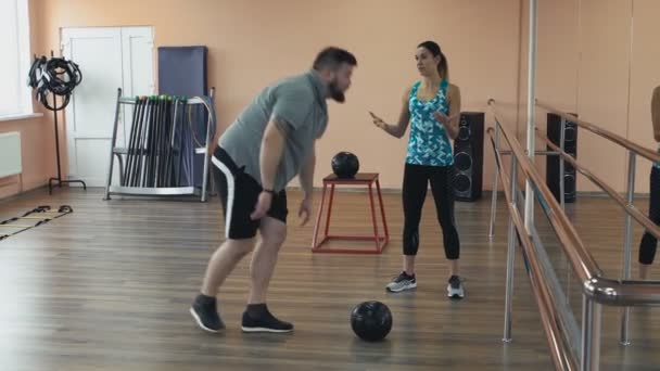 Överviktig manliga och kvinnliga tränare med perfekt kropp bränna kalorier vid träning. Personlig träning från atletisk flicka för fatboy med stora buken i sportkläder. Fet man träning med kvinna instruktör — Stockvideo