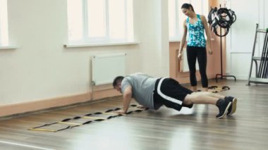 Kişisel ince Koç ile birlikte kalın obez adam fiziksel pislik içinde jimnastik salonu var. Kusursuz bir beden ile kilolu erkek ve kadın eğitmen tarafından egzersiz kalori yakmak. Kişisel eğitim için atletik kız dan