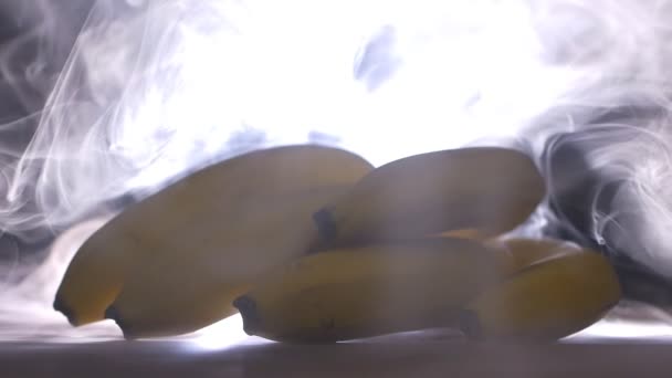 A bunch of juicy and ripe bananas on the background of smoke and freshness, evaporation, close-up, slow motion — Stock Video