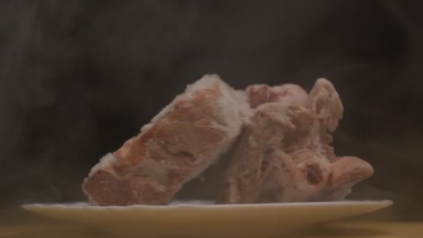 Pieces of frozen rotating meat on a black background, from which blows frosty freshness and cold, smoke, close-up, slow motion — Stock Video