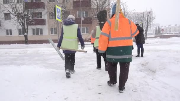 Bobruisk, Bělorusko - 14. ledna 2019: Údržbáři v signální vesty s lopatami projít zimní město, pomalý pohyb — Stock video