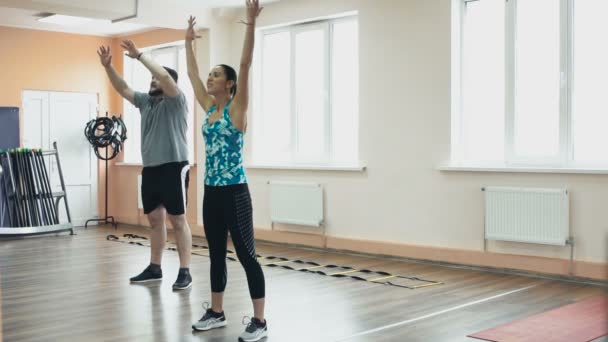 Fet man träning med kvinnliga instruktör och gör övningar i gymmet. Tjocka feta killen tillsammans med personliga smal coach gör fysiska ryck i gymmet. Överviktiga män och kvinna tränare med — Stockvideo