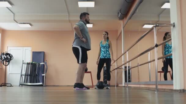 Entrenamiento personal de chica atlética para gordito con gran abdomen en ropa deportiva. Hombre gordo entrenando con instructora y haciendo ejercicios en el gimnasio. Grueso obeso chico junto con personal — Vídeos de Stock