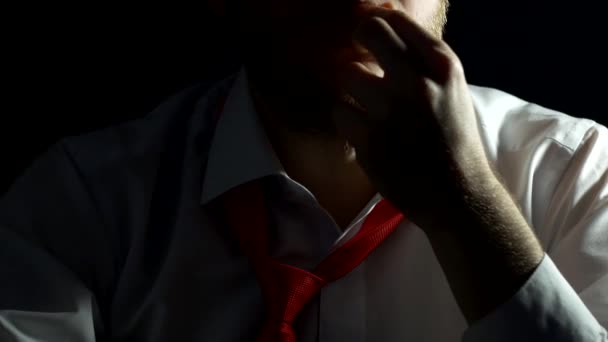 Een man in een wit overhemd met een baard lijnen en raakt zijn baard is nerveus. zwarte achtergrond dicht omhoog, zakenman — Stockvideo