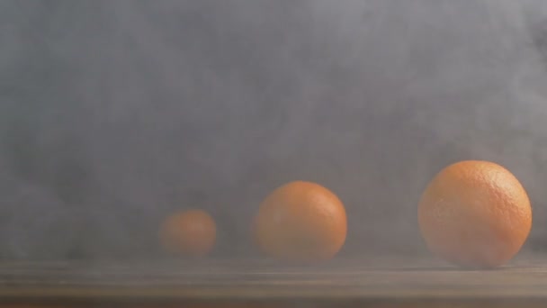 Tangerinas ou mandarinas rolam através da mesa na fumaça em câmera lenta — Vídeo de Stock