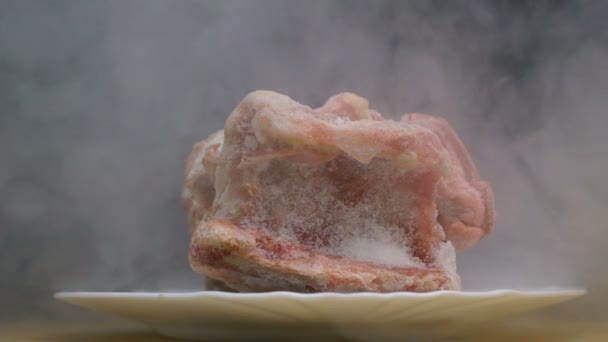 Stück gefrorenen Schweinebauch oder Rindfleisch auf einem Teller pusten durch Rauch in slowmo — Stockvideo