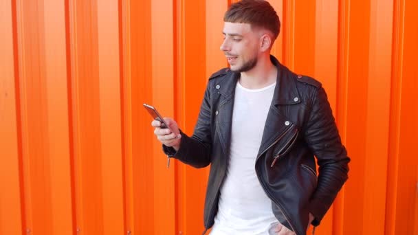 Hungry Unshaven Young Man Examines Food Phone Licks Orange Background — Stock Video