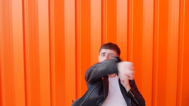 Unga glada kaukasiska kille med skägg fipplat och slåss på kamera, orange bakgrund, långsamma-mo — Stockvideo