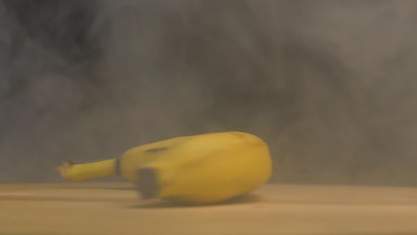 Rotativa de banana madura em fumaça e frescura em um fundo preto. close-up, câmera lenta — Vídeo de Stock