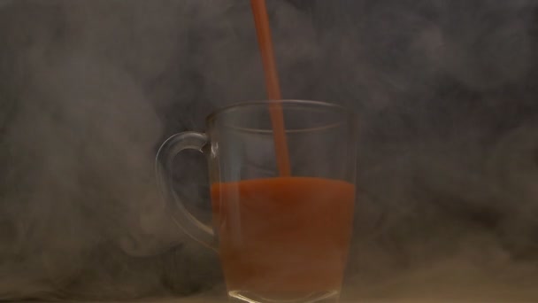 Em uma xícara que gira suco de tomate fresco é derramado na fumaça, fundo preto, câmera lenta, brevidade — Vídeo de Stock