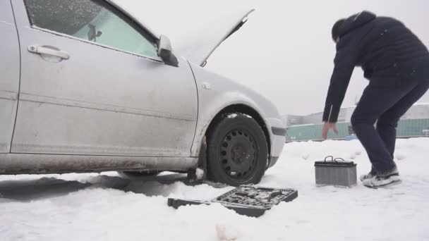 Un hombre instala una batería de coche en un coche, arranque frío de invierno de un montaje de automóvil diesel, cámara lenta, acumulador — Vídeo de stock