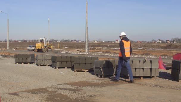 Інспектор перевіряє якість дорожнього бордюру під час будівництва дороги, інженер — стокове відео