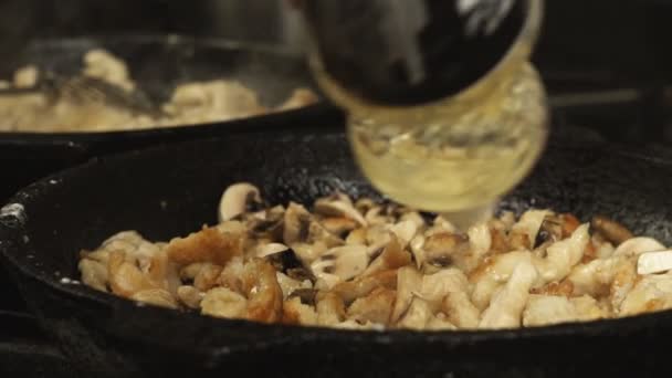 Koken giet plantaardige of zonnebloemolie op stukjes vlees in de koekenpan of koekepan in slow motion — Stockvideo