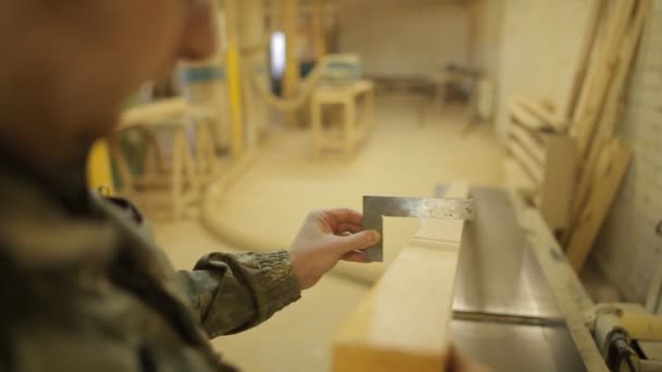 Een werknemer in de Timmer winkel controleert de hoek van het bord op de zagerij met een vierkant, close-up, verwerking — Stockvideo