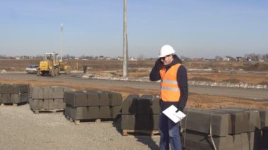 Öfkeli ve sinirli patron siyah gözlük ve koruyucu bir kask üzerinde telefon nevrno yol inşaatı zemin üzerine konuşuyor