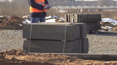 Bir denetçisi'nde bir sinyal yelek ve siyah gözlüklü beyaz kask kalitesini yol kaldırım ve yol yapımı, yol çalışması onun klasöründe notlar yapar