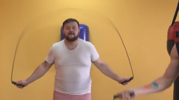 Dicker bärtiger Kaukasier wärmt sich vor dem Training auf und springt über das Seil — Stockvideo