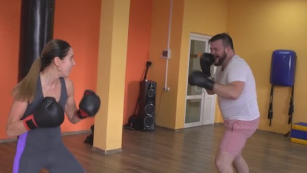 Чоловік і жінка жартують, бореться в боксерських рукавичках в спортзалі, повільний рух — стокове відео