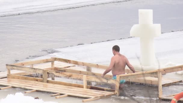 Een man baadt in het ijsgat in koud water in de winter voor de doop vakantie, 4k — Stockvideo