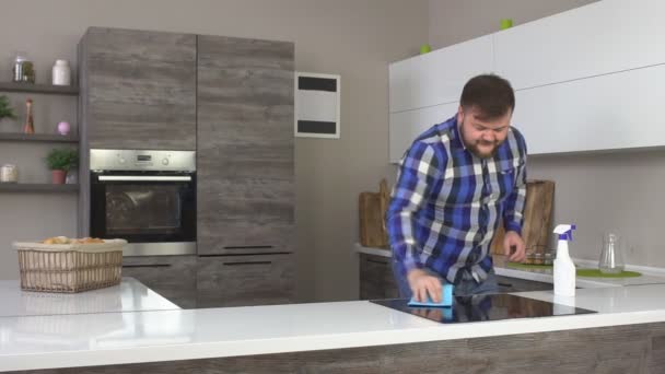 Веселый бородатый мужчина моет столешницу на кухне и танцует, замедленное движение, интерьер — стоковое видео