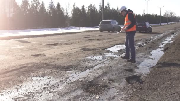 Inspecteur onderzoekt en controleert gaten in de weg, slechte weg — Stockvideo