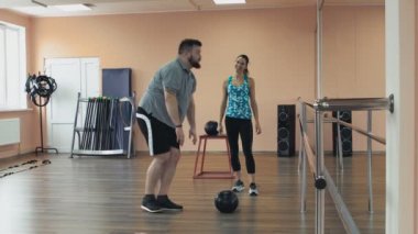 Kişisel eğitim için spor giyim büyük karın ile fatboy atletik kızdan. Şişman adam kadın öğretim üyesi ile eğitim ve fitness Center'da egzersizleri yapıyor. Kişisel birlikte kalın obez adam