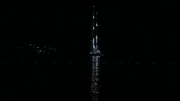 Barco yate o barco velero está en el mar por la noche con reflejos de luz en el agua — Vídeos de Stock