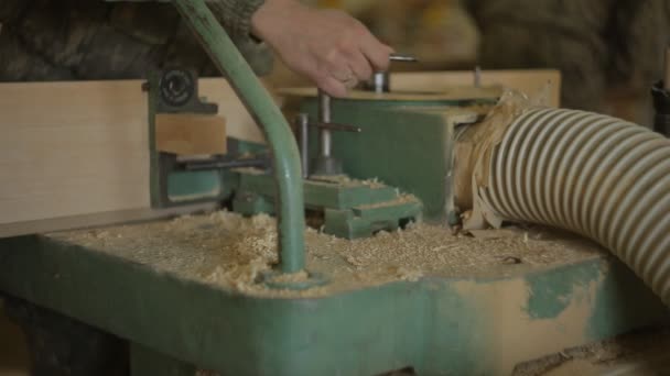 Los trabajadores en el aserradero cambian las cortadoras en la máquina de cantos y configuran la máquina para el procesamiento de madera, primer plano, carpintero, sierra eléctrica — Vídeo de stock