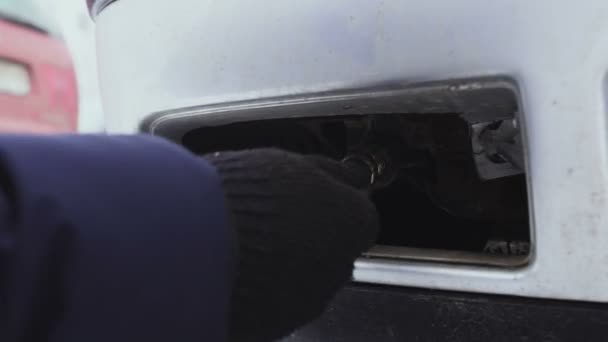 Muž šroubování závěsné smyčky do auta, close-up, zimní — Stock video
