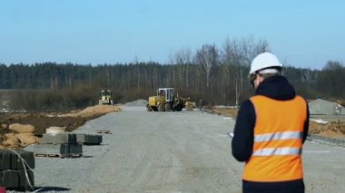 Mühendis Müfettiş görünüyor ve kaldırım malzeme veya platform döşeme önce yol yapım aşaması sırasında verileri yazar