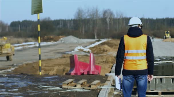 Інспектор спостерігає за процесом будівництва доріг перед укладанням дорожнього покриття або тротуарного матеріалу важким будівельним обладнанням — стокове відео