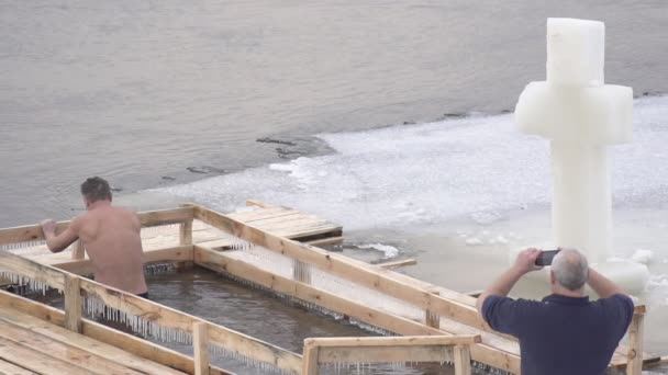 Bobruisk, 벨로루시-1 월 19 일, 2019: 남자 목욕 하 고 겨울에는 강에 만든 얼음 글꼴에 잠수, 휴일은 침례, 슬로우 모션 — 비디오